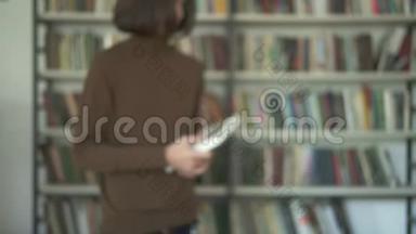 一个模糊的男学生从图书馆的书架上拿起一本书