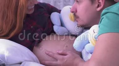 爸爸亲吻和抚摸妻子玩软玩具的肚子。 <strong>生育</strong>观念。 怀孕。 <strong>家庭</strong>幸福。
