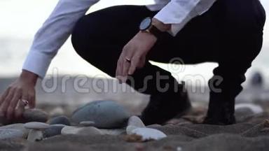 海滩上的人试图用灰色的石头建造金字塔，但这并<strong>不容</strong>易，石头掉了下来。