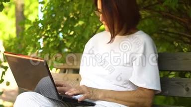 <strong>中年</strong>妇女在户外的笔记本电脑上工作，微笑的<strong>中年</strong>祖母在电脑上遥远地工作。