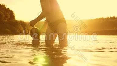 快乐的爸爸和快乐的微笑的宝宝，在金色的夕阳下在水中洗澡和玩耍。 爸爸和小女儿在玩