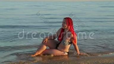 一个穿着泳衣的女人坐在<strong>海浪汹涌</strong>的海岸上