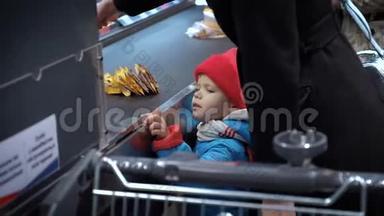 一个小孩站在超市<strong>收银台</strong>附近看货