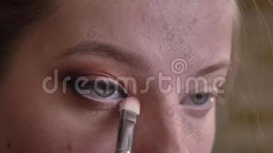 年轻的白种人女化妆师将白色眼影贴在<strong>眼角</strong>上的特写肖像