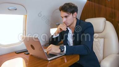 年轻的商人在私人飞机上用笔记本电脑工作。 成功的商业百万人头等舱旅行