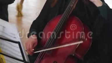 女人用大提琴弓演奏大提琴。 年轻的音乐家女孩演奏大提琴中提琴