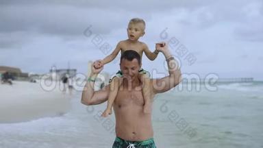 年轻的<strong>父亲和</strong>他的小<strong>儿子在</strong>海滩上玩得很开心。 <strong>儿子</strong>坐<strong>在</strong>爸爸`肩膀上