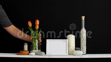 现代客房装饰与相框模型。 用装饰蜡烛、玻璃和岩石搭在黑色墙壁上。 手把手
