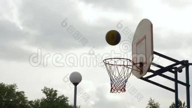把球扔到户外的篮球圈里。 篮球运动员在运动场上掷球. 篮球进球