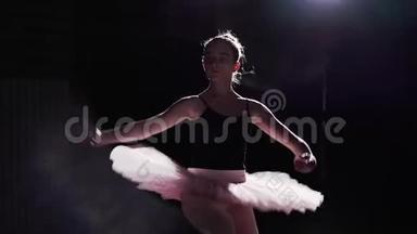 灵活的女孩在她的尖形芭蕾<strong>舞鞋</strong>上跳舞，聚光灯下的黑色背景在工作室。 专业青年