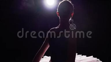 漂亮的年轻芭蕾舞演员站在她的尖角芭蕾<strong>舞鞋</strong>上，聚光灯下的黑色背景在演播室。 女孩表演