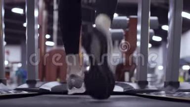 在健身房跑步机上运动的女人的运动鞋上观看