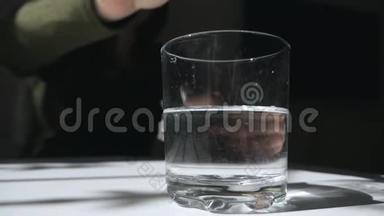 一片泡腾的止痛片落入玻璃杯中溶解。 阿斯匹林药片在玻璃杯里。 治疗