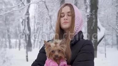 一位留着长发的孤独可爱女孩拥抱着一只穿着羊毛衫的约克郡猎犬，双手抱着狗