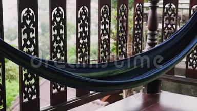 阳台上的吊床可以俯瞰绿色植物，有一个多色吊床。 假期及假期概念