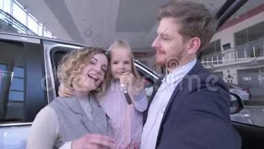 一家人带着可爱的小女儿，带着钥匙，在新买的汽车附近打电话拍照。