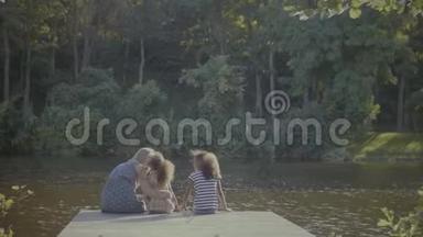 可爱的家庭在池塘边的木墩上放松