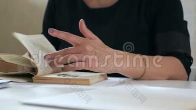 女人在一本悠闲的书中翻阅，坐在白色的桌子旁