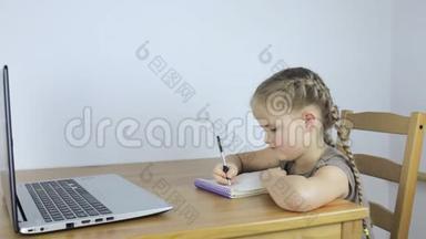 在网上学习的小女孩，在笔记本上写字