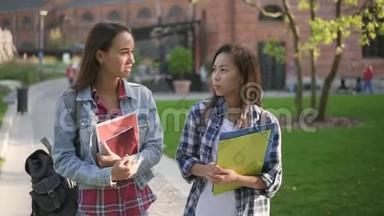 亚洲和白种人大学生在校园里散步，谈论教育。