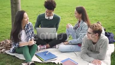 年轻的<strong>学生</strong>坐在草地上，快乐地在一起<strong>聊天</strong>。