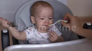妈妈用勺子喂她可爱的宝宝。 小男孩正在吃儿童粥