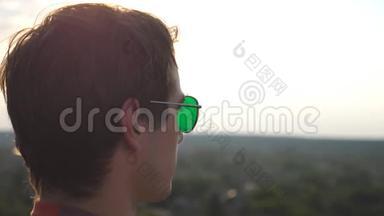 从<strong>高楼大厦</strong>的屋顶观看城市全景的年轻人戴着太阳镜。 帅哥看起来
