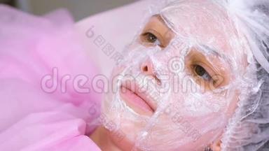美容师把一张塑料薄膜贴在<strong>保湿面膜</strong>上面，贴在女人`脸上。