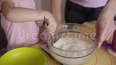 小女孩穿着粉红色的衬衫，在厨房里和她的母亲<strong>一起</strong>在碗里搅拌面粉。 <strong>一起</strong>做饭，和孩子<strong>一起</strong>烘焙