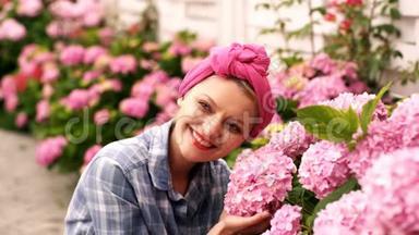 女人在乡下房子里关心粉红色的花。 <strong>爱护</strong>花朵的观念.. 令人难以置信的美丽的粉红色花蕾