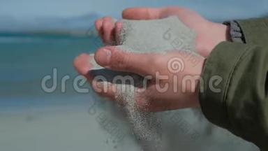 人手中的沙子.. 近距离观察沙子穿过一个人的手。 从手中掉落的沙子