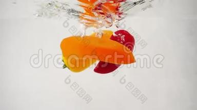 三个新鲜的五颜六色的甜椒倒在水中央，溅起泡泡