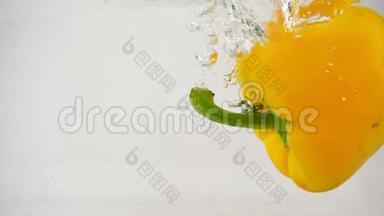 一个黄色的钟状甜辣椒落入水的右边，溅和气泡