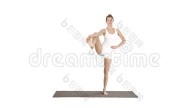 美丽的微笑，快乐的年轻女子在垫子上做瑜伽运动，站在Vrksasana姿势上，树状体式穿在白色上
