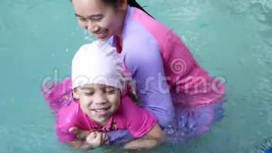 亚洲小女孩学游泳，妈妈在暑假期间在游泳池里照顾孩子