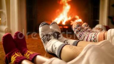 特写4k视频的家人躺在毯子下穿着<strong>温暖</strong>的羊毛袜子<strong>温暖</strong>的壁炉火。 人民