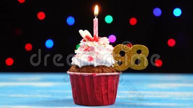美味的生日蛋糕，燃烧的蜡烛和98号彩灯背景