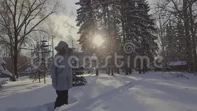 在弗罗斯特冬季公园，一个戴着灰色帽子和灰色羽绒服的女人从一个透明的桶里倒开水