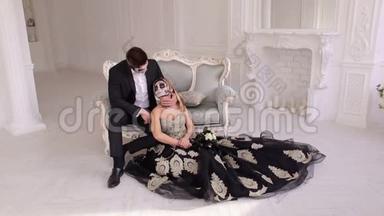 一对打扮得诡异的万圣节夫妇坐在老式房间的老式沙发上。