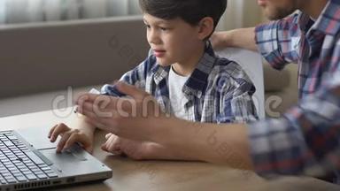 <strong>父亲帮助</strong>儿子做笔记本电脑作业，接受现代技术教育
