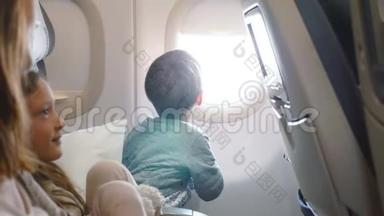 快乐的小男孩在和家人<strong>一起去</strong>度假旅行时，从飞机的窗口座位上欣赏风景。