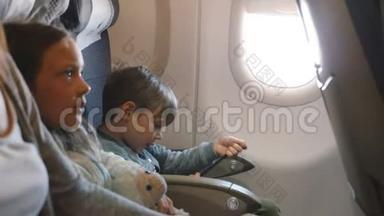 从侧面看，小无聊的男孩和<strong>女孩</strong>在飞机飞行中娱乐自己，<strong>去度假</strong>与家人。