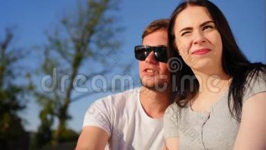 浪漫的夫妻喝咖啡，坐在公园的绿草上。 夫妻信任，爱和幸福的概念。 中等