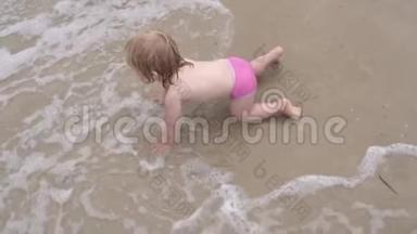 婴儿在波浪中在水面上<strong>爬行</strong>。 小女孩在沙滩上潮湿的沙滩上<strong>爬行</strong>..