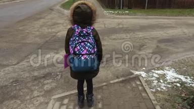 放学后带背包的小女孩试着过马路