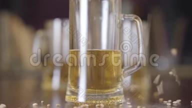 酒吧特写中站在桌子上的那杯啤酒.. 大麦种子洒在玻璃旁边.. 天然啤酒