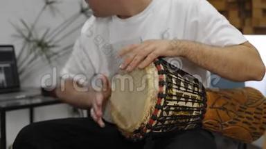 在家庭音乐工作室演奏djembe鼓乐器时手腕疼痛的音乐家。