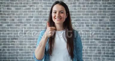 快乐学生的画像，在砖墙的背景上竖起大拇指微笑