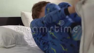 两个兄弟躺在铺着白色毯子的床上，然后孩子站起来在床上跳舞
