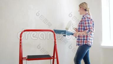 4k视频年轻女子拿着调色板，用油漆滚筒在她的房子里粉刷墙壁